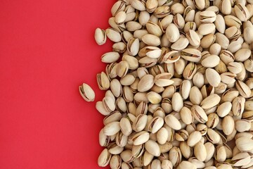 Tasty unpeeled pistachios on bright red background, top view flat lay background pattern
