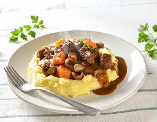 Savory Beef Stew with Carrots, Mushrooms, Olives on Creamy Mash, Fresh Parsley Garnish.