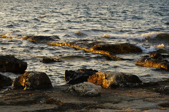 Beautiful sunset at the Adriatic Sea with waves and rck with golden light