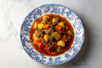 Beef goulash, soup and a stew, made of beef chuck steak, potatoes and plenty of paprika. Hungarian  traditional meal.