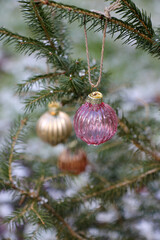 Small multi-colored glass balls on an outdoor Christmas tree close-up.