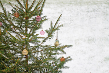 A Christmas tree  with decoration on a snowy lawn close-up.