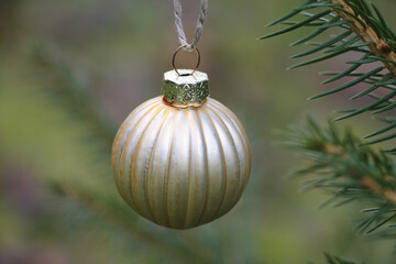 Vintage style gold Christmas decoration on a tree outdoors close-up.