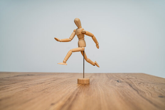 A wooden mannequin figure poses in mid-run, set against a soft-colored backdrop, creating a dynamic sense of motion on a textured wooden table.