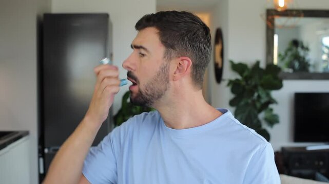 Asthmatic man using an inhaler at home 