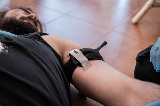 Paramedic applying tourniquet on injured man during first aid training - Powered by Adobe