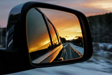 Sunset and road reflection in the side mirror of a black car