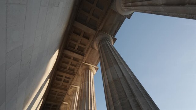 Blick nach oben auf maechtigen Marmorsaeulen Walhalla bei Regensburg, Bayern, Deutschland. Im goldenen Licht des Sommerabends strahlen die klassizistischen Kolonnaden eindrucksvoll gegen den Himmel