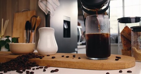 Glass, kitchen and pour ice coffee with plunger for drink preparation, espresso or morning brew. Caffeine, jar and cold beverage with cubes, liquid and hands of person with french press at home - Powered by Adobe