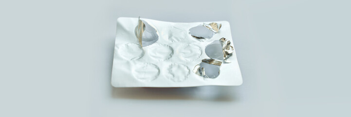 Empty blister pack with silver foil on light background signifying used medication.