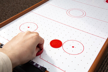 Hand ready to hit with paddle on puck. The portable table hockey includes plastic hockey paddles, a mini puck and score keepers. Hobby game background with copy space. High quality