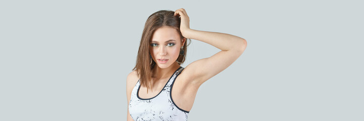 Obraz premium Young caucasian female with brown hair in marble-patterned top posing against light gray background.
