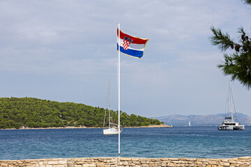 Fototapeta premium Croatian Flag Over Seaside With Boats At Sunny Coastal Scene