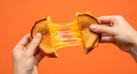 Hands pulling apart a grilled cheese sandwich with stretchy melted cheese against an orange background, showcasing its gooey texture.