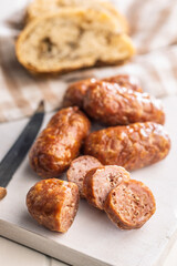 Photo of roasted italian sausage salsiccia on cutting board on white table.