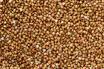 Textured organic food background of dry uncooked green buckwheat kernels