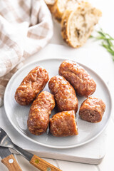 Photo of roasted italian sausage salsiccia on plate on white table.