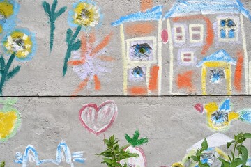 Colorful flowers,animal,and a houses on the damaged fence,a child`s drawing.