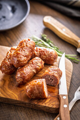 Photo of roasted italian sausage salsiccia on cutting board on wooden table.