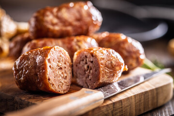 Photo of roasted italian sausage salsiccia on cutting board on wooden table.