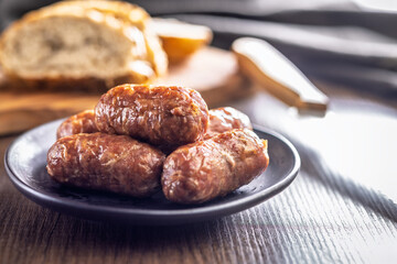 Photo of roasted italian sausage salsiccia on plate on wooden table.