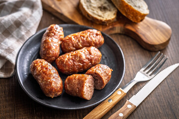 Photo of roasted italian sausage salsiccia on plate on wooden table.