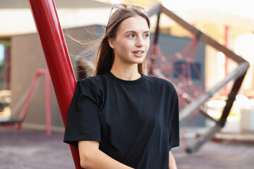 Obraz premium Young woman wearing blank black t-shirt outdoors. Mockup for design