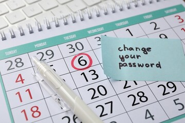 Note with phrase Change your password, calendar, pen and keyboard, closeup