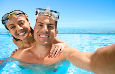 Couple taking selfie in infinity swimming pool with view on ocean