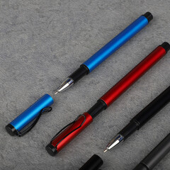Three Color Black, Red, Blue  Ballpoint Pens On Gray Carpet Surface For Office And Stationery Photo