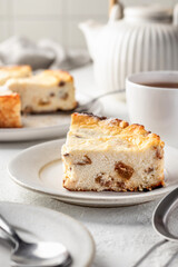 A piece of homemade cottage cheese casserole pie with raisins close up. Baked cheesecake for healthy breakfast on white table background