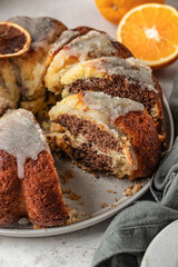Sliced orange and chocolate bundt cake with sugar icing close up. Fruity citrus dessert on light gray kitchen background