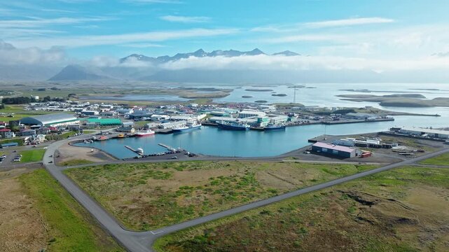 Hofn harbor and marina Iceland. The drone moves across the harbor showing trawlers, cargo ships, and reflections in the still morning water.