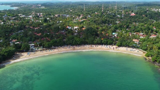 Stunning aerial drone view of a tropical paradise beach near Dondra Head, the southernmost point of Sri Lanka, with turquoise water and lush palm trees.