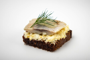 a piece of herring with dill on dark bread