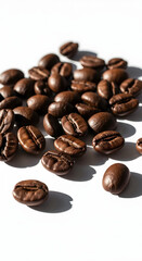 Fototapeta premium A close-up shot of roasted coffee beans scattered on a white surface, casting soft shadows.