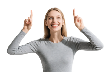 A joyful woman in a gray top is pointing upwards with both hands, showing a positive and cheerful expression.