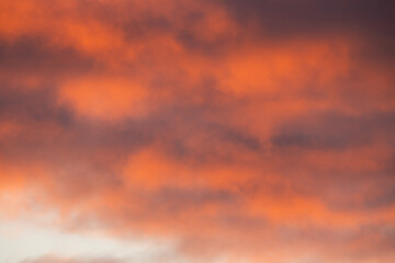 Fiery orange and dramatic purple clouds fill the sky during a beautiful sunset, creating a colorful and abstract background.