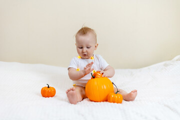 Baby Playing with Halloween Pumpkin on Bed