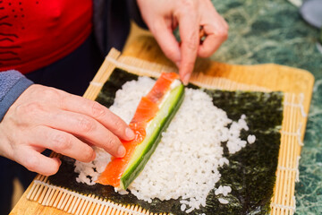 Hands Assembling Vegetable Maki Sushi Roll on Bamboo Mat © mettus
