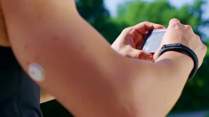 Tight shot of a fit man checking his glucose levels with wearable sensors during an outdoor run in a scenic park. - Powered by Adobe