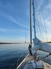 Sailor Standing on Yacht Foredeck Heading Towards Horizon.
