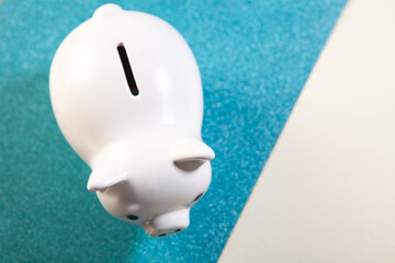 White piggy bank on a blue and white background with copy space