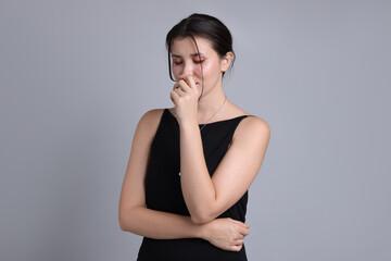 Fototapeta premium Woman in dress crying on grey background