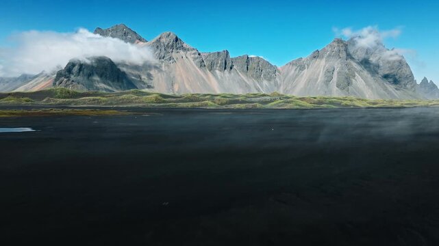 Vestrahorn mountains and black dunes Iceland. Drone captures expansive volcanic landscape merging with the sea horizon.