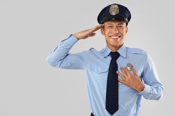 Young policeman in uniform on light grey background