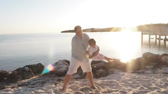 Father Swinging Son on Beach at Sunset, Joyful Family Moment in the Florida Keys