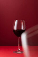 Still life of elegant glass of red wine on a deep red background with soft reflections