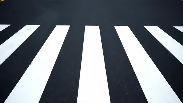 A direct overhead view of a pedestrian crossing marked with bold white stripes on a dark asphalt road, emphasizing safety and urban passage.