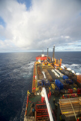 A semi-submersible heavy lift ship underway at sea under dramatic sky